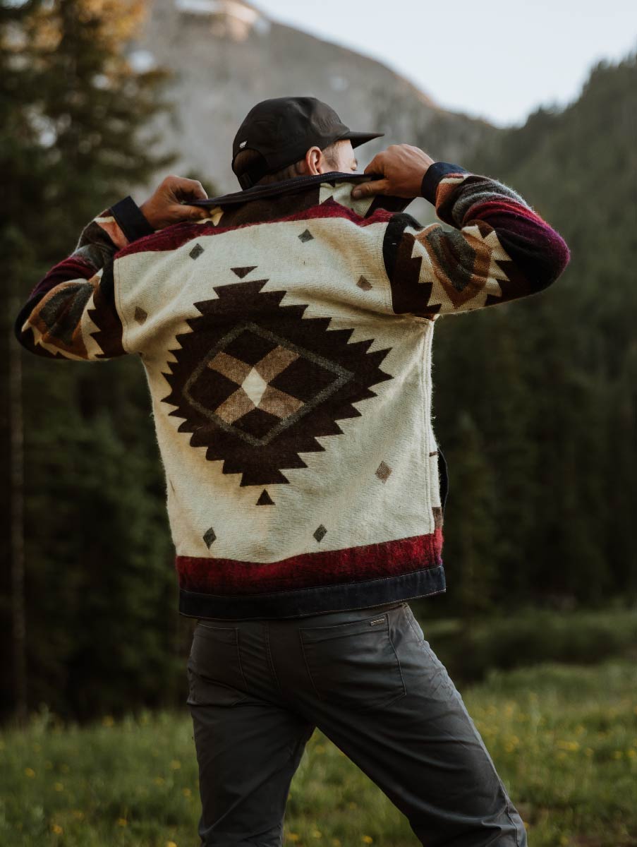 Back of the Peguche Jacket showing the woven Andean diamond motif, worn in a mountain forest