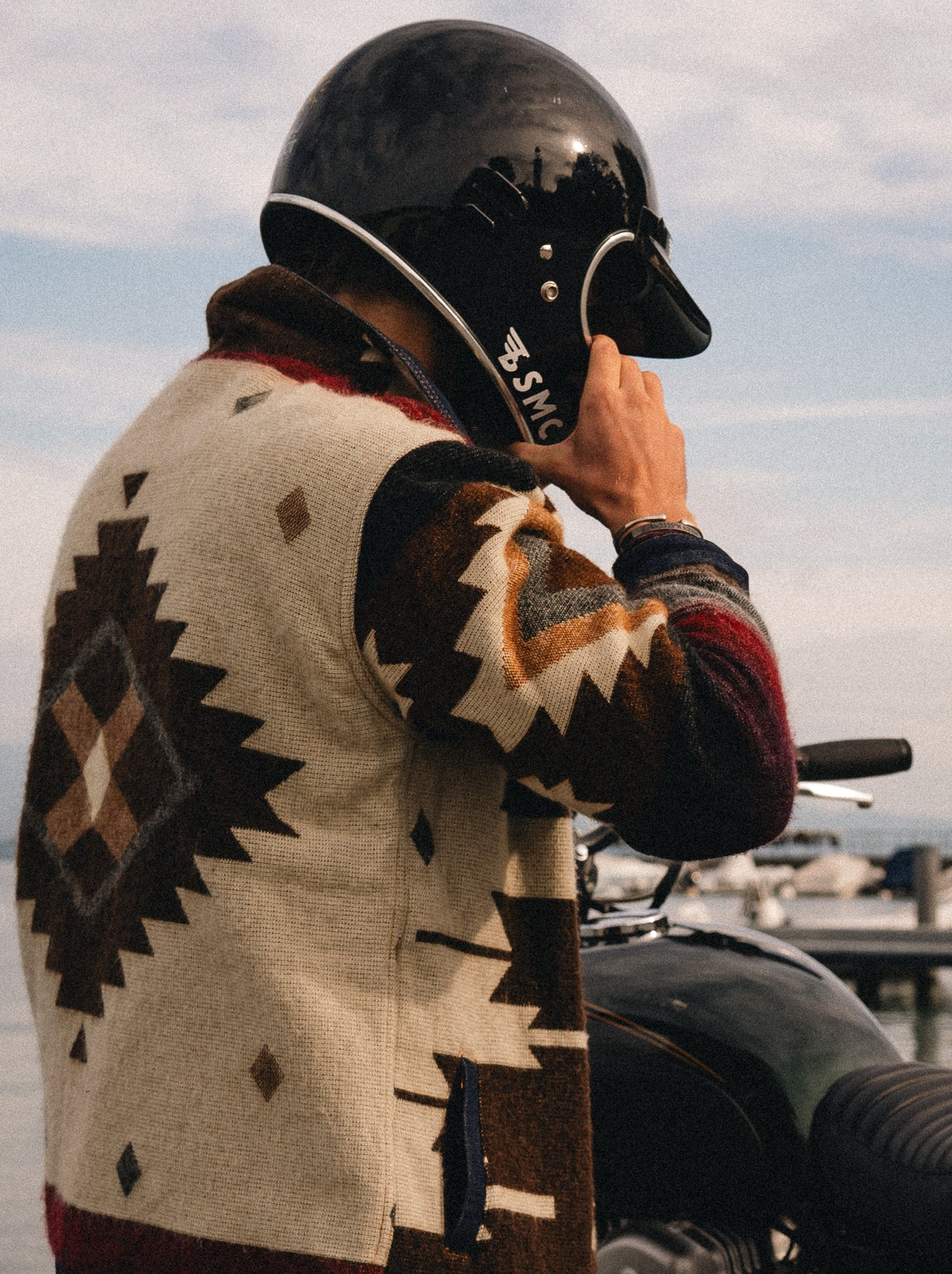 Motorcyclist in a black helmet wearing the Peguche Jacket, cream wool with brown Andean diamonds