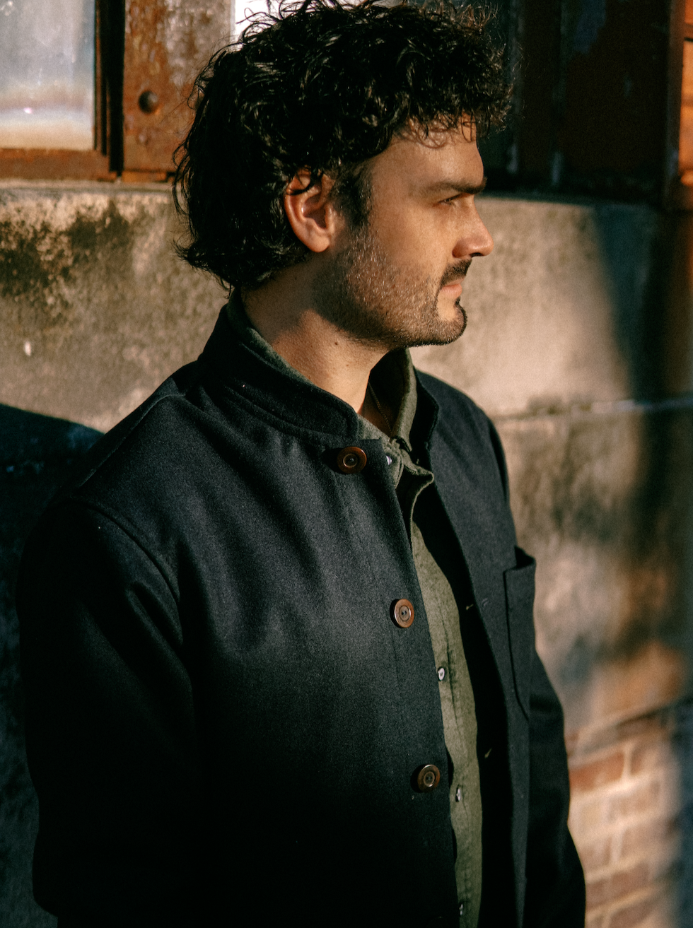 Man in profile wearing the Tambo Wool Jacket in Navy with a band collar
